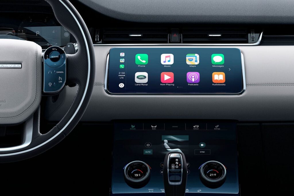 Modern Land Rover car interior showing touchscreen display with phone, music, maps, and messaging apps on dashboard