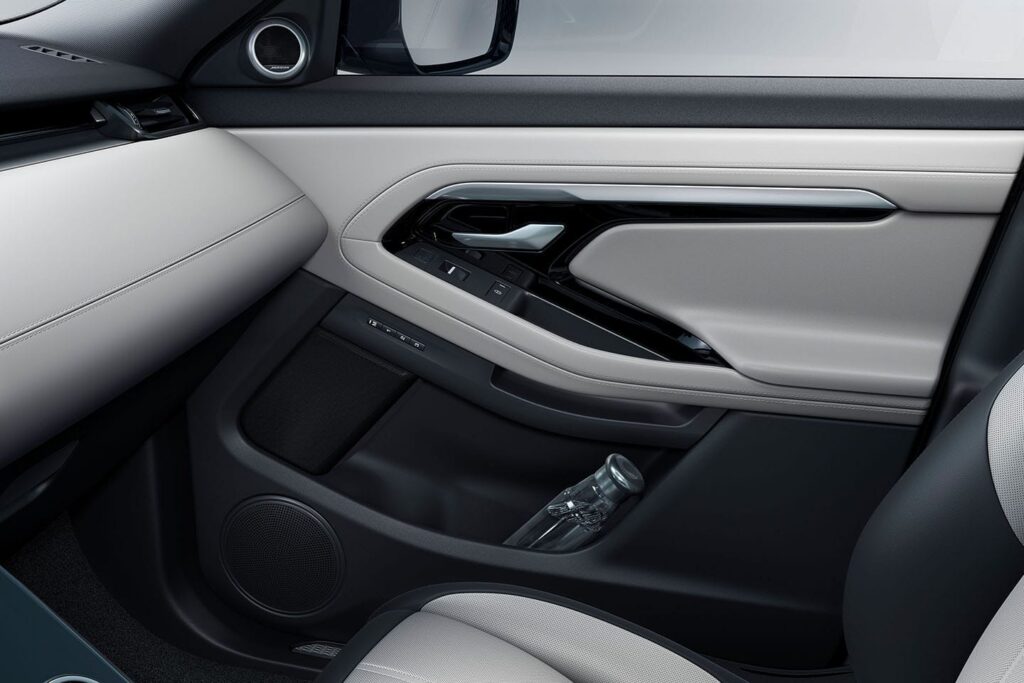 Light grey and black car door panel featuring integrated controls and a bottle stored in the door compartment