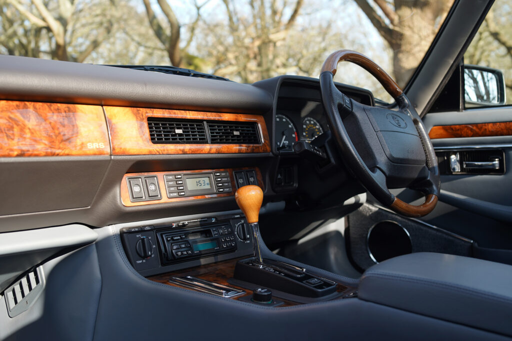 Stylish vintage car interior featuring a wooden steering wheel and gear shift lever with wood panel dashboard accents