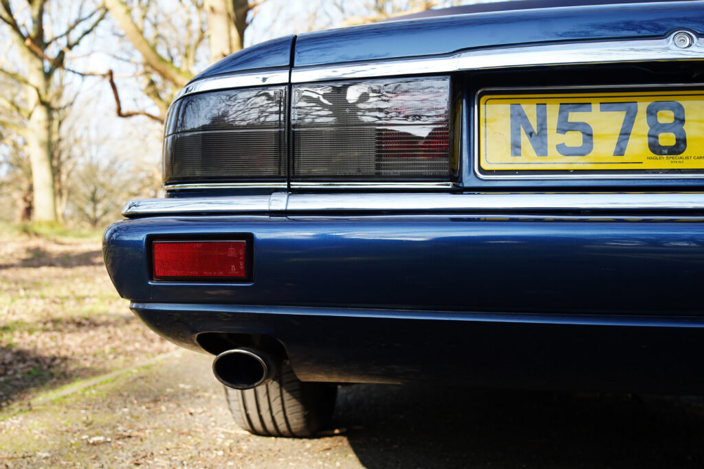 Rear section of a blue classic car showing the tail light, exhaust pipe, and yellow UK number plate N578