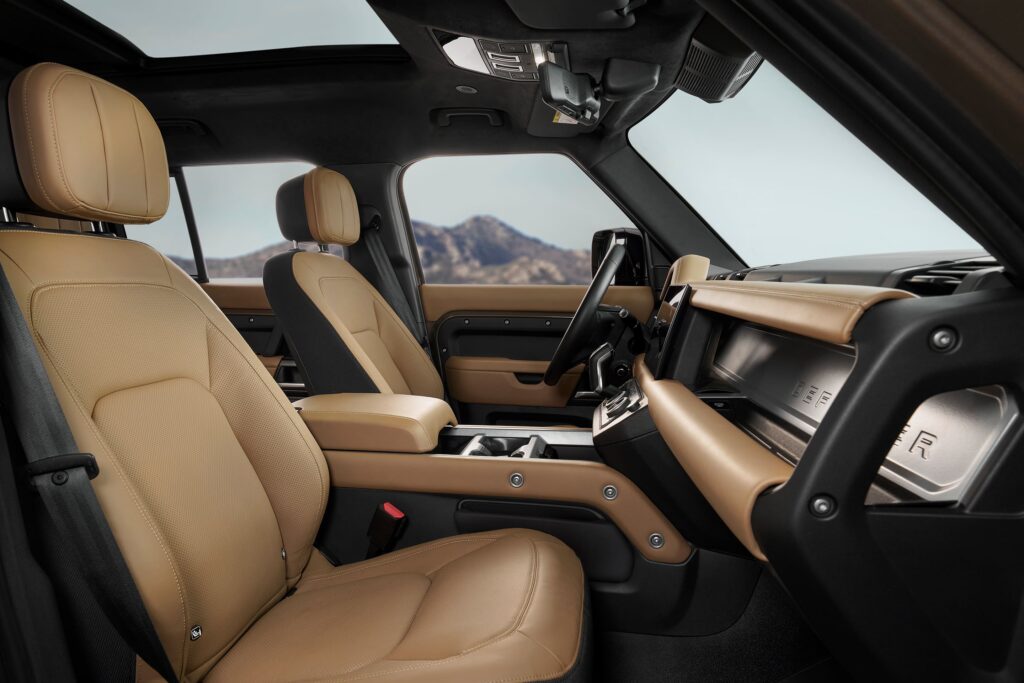 Luxury car interior featuring tan leather seats and modern dashboard design with mountain view outside, highlighting comfort and style