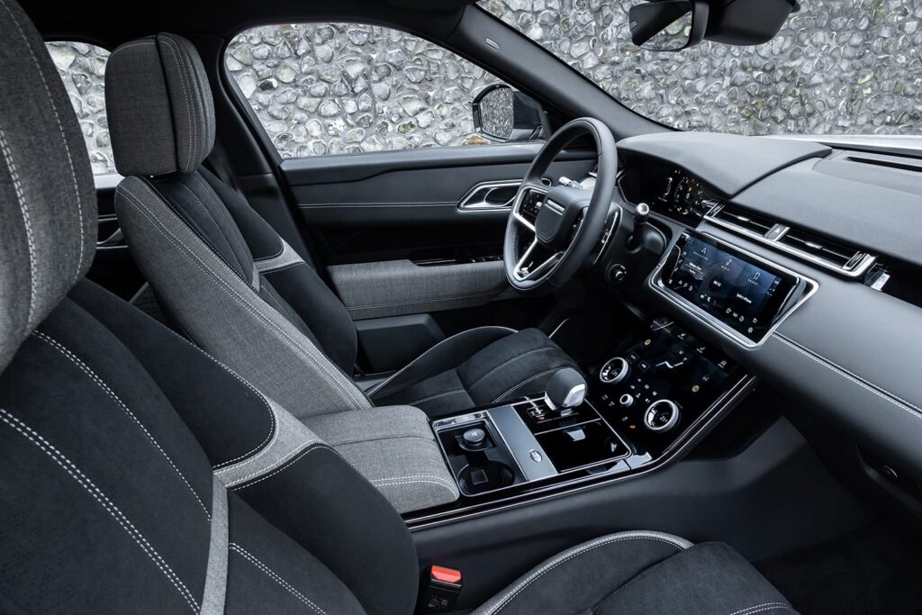Modern car interior featuring two-tone fabric seats, a digital dashboard, central touchscreen, and sleek control panel