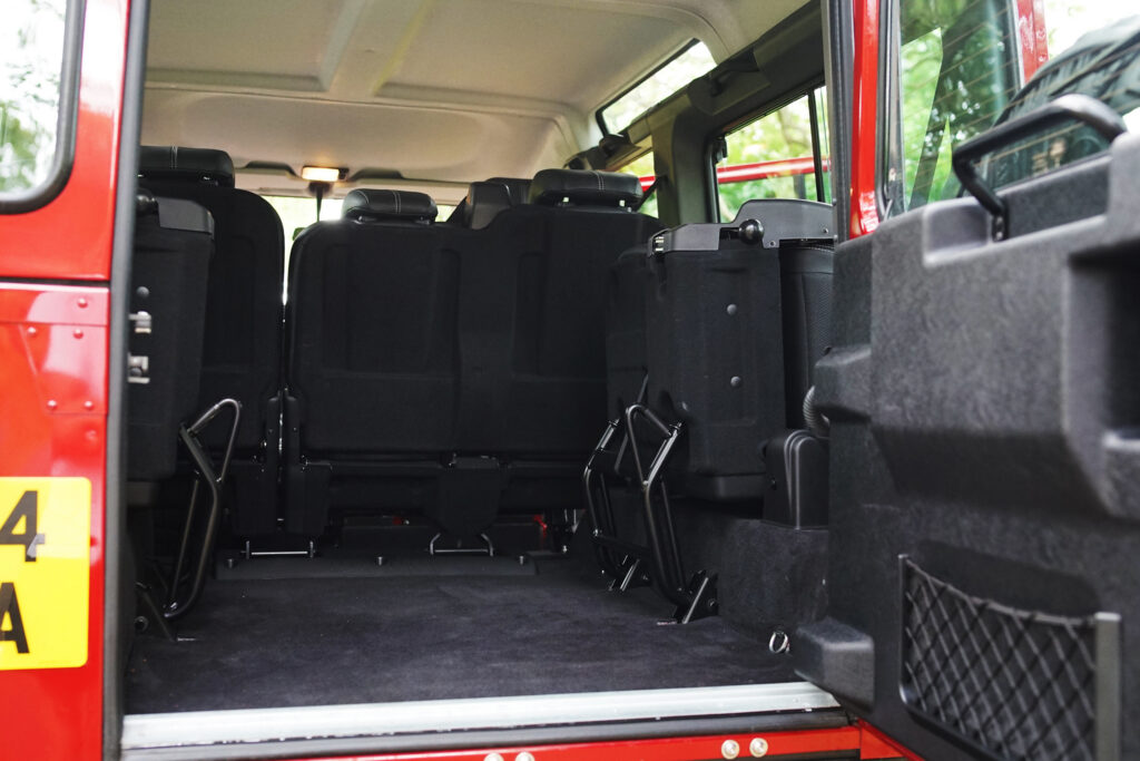 The open rear door reveals the spacious cargo area and folded seats inside a red off-road vehicle.