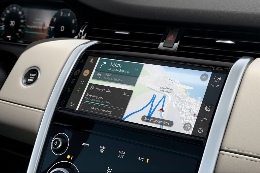 Car dashboard touchscreen displaying navigation map with rerouting notice for heavy traffic on Moyenne Corniche route