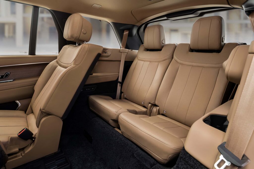 Rear tan leather seats and partial front seat inside a car interior with luxurious finishes.