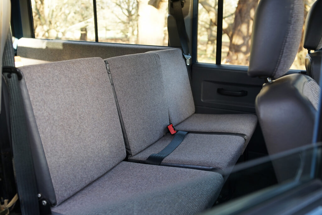 Grey fabric rear seats with seat belts inside a vehicle interior, including visible window and door panel details.