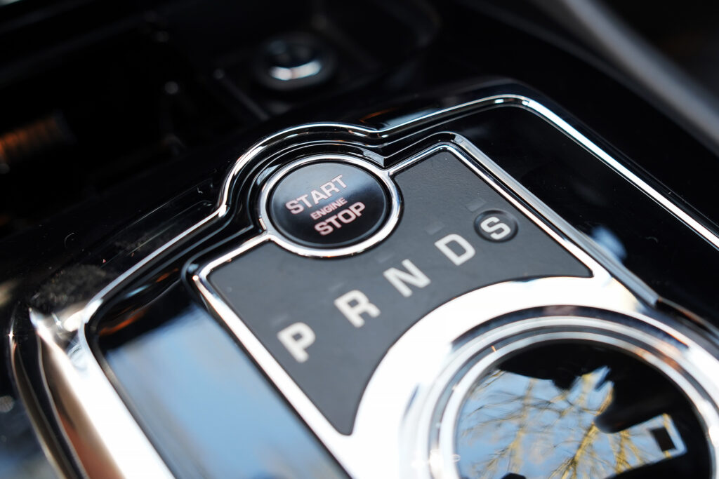 Close-up of the start engine stop button and automatic gear selector showing letters P R N D S with chrome trim inside a car