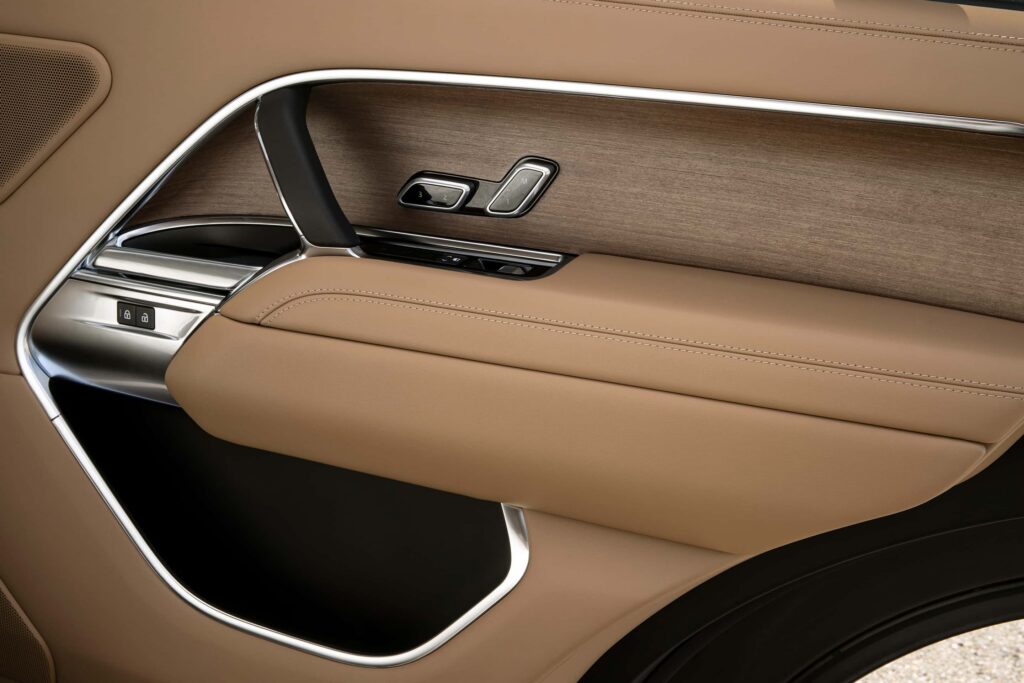 Detail of a luxury car door panel featuring tan leather upholstery, wood trim, metal accents, and memory seat adjustment buttons.