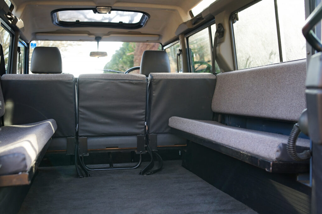 Spacious rear interior of an off-road vehicle showing bench seating on the sides and two front seats under a roof window