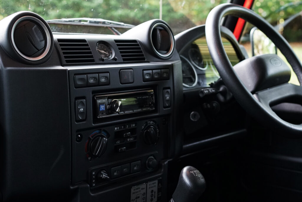 Classic car interior showing the dashboard, steering wheel, gear stick and radio controls clearly.