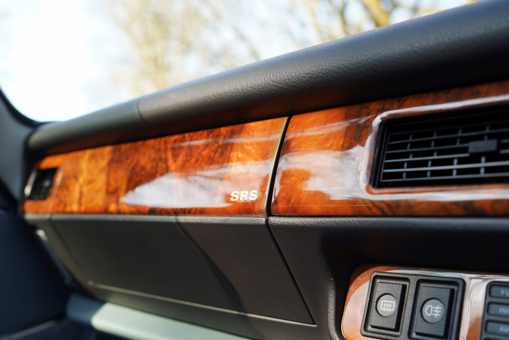 Dashboard interior featuring polished wood panels with SRS label and air vents in a classic car