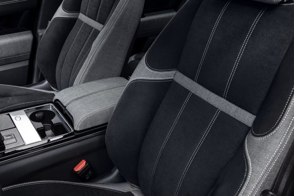 Black and grey fabric car seats next to a centre console with cup holders and control buttons.