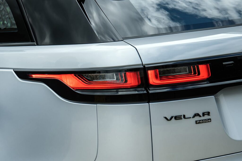 Close-up of the illuminated rear lights and Velar P400e badge on a white Range Rover Velar classic SUV