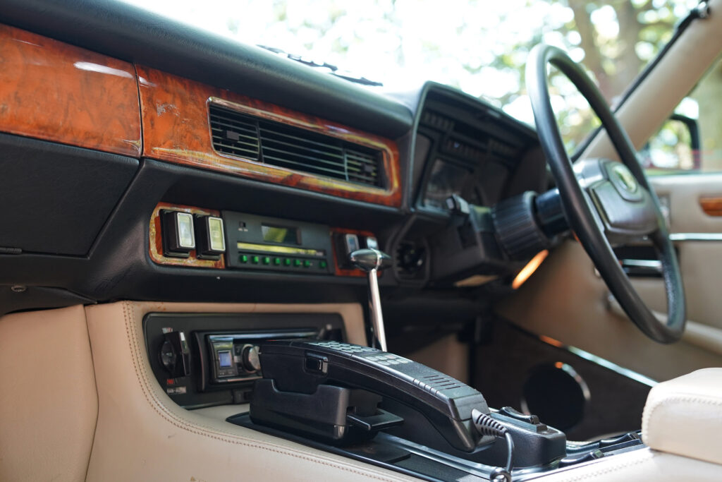 Classic car interior showcasing a dashboard with wood accents and a vintage car phone on the center console